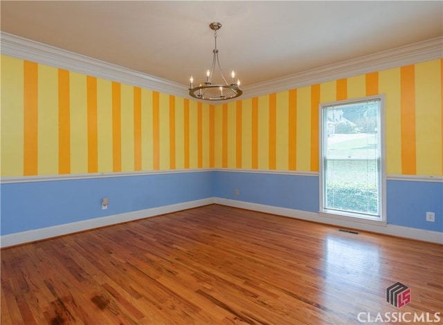 unfurnished room with a chandelier, crown molding, wood finished floors, and baseboards