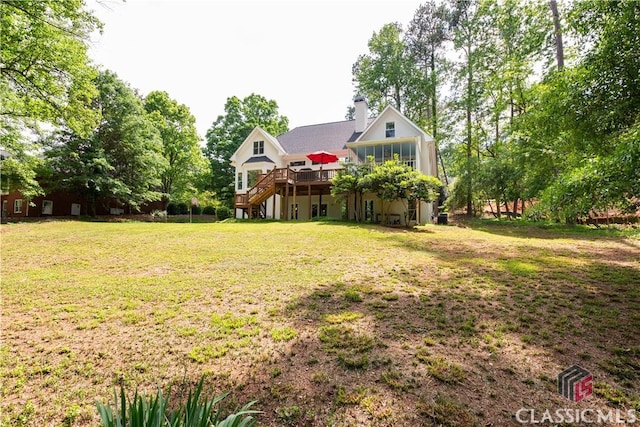 view of green lawn featuring a wooden deck and stairs