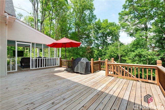 wooden deck with view of wooded area and area for grilling