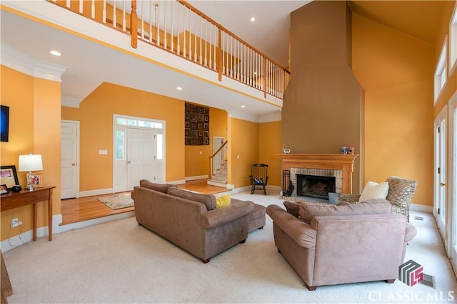 living area with a high ceiling, stairs, a fireplace, crown molding, and baseboards