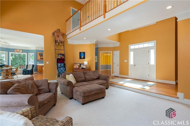 living room featuring a towering ceiling, crown molding, baseboards, and recessed lighting