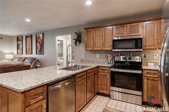 2100 New Hope Church Rd, Comer, GA 30629 - kitchen with stainless steel appliances, a sink, a peninsula, open floor plan, and brown cabinetry