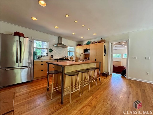 160 Gran Ellen Dr, Athens, GA 30606 - kitchen featuring appliances with stainless steel finishes, wall chimney exhaust hood, light wood-style flooring, recessed lighting, and a kitchen bar