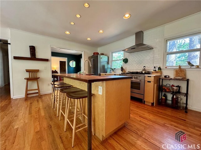 160 Gran Ellen Dr, Athens, GA 30606 - kitchen featuring wall chimney range hood, stainless steel appliances, recessed lighting, light wood finished floors, and a center island with sink