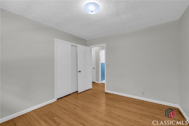 1119 John W Breedlove Rd, Monroe, GA 30656 - unfurnished bedroom with baseboards, light wood finished floors, a closet, and a textured ceiling