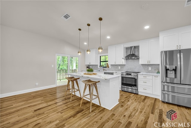 3920 Old Lexington Rd, Athens, GA 30605 - kitchen with appliances with stainless steel finishes, wall chimney exhaust hood, a kitchen island, light wood finished floors, and white cabinets
