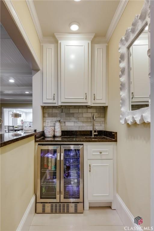 155 Wexford Pl, Athens, GA 30609 - indoor wet bar featuring wine cooler, decorative backsplash, baseboards, light tile patterned flooring, and crown molding