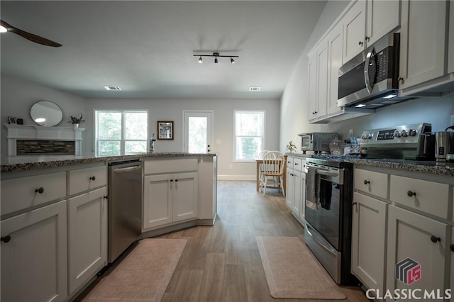 35 Westwood St, Danielsville, GA 30633 - kitchen with stainless steel appliances, light wood-style floors, stone countertops, white cabinetry, and ceiling fan