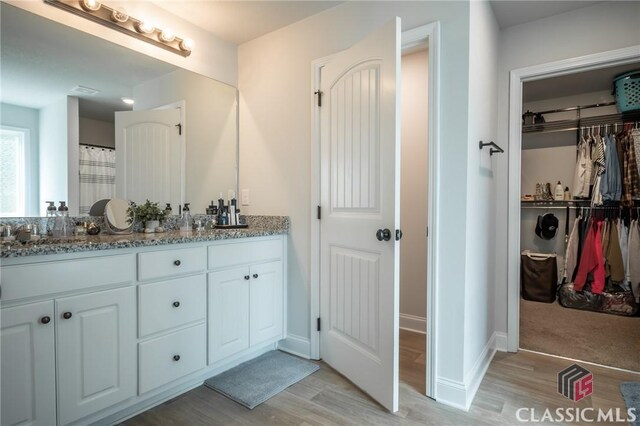35 Westwood St, Danielsville, GA 30633 - bathroom with wood finished floors, double vanity, a spacious closet, and baseboards