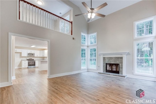4085 Fawn Vly, Loganville, GA 30052 - unfurnished living room featuring high vaulted ceiling, light wood-style floors, ceiling fan, a fireplace, and baseboards