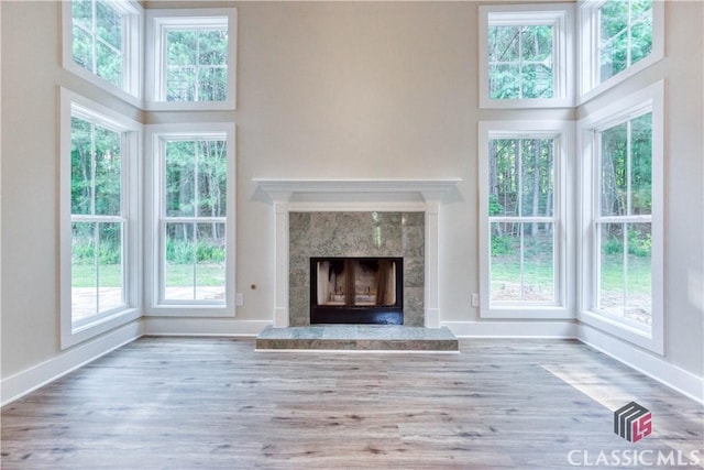4085 Fawn Vly, Loganville, GA 30052 - unfurnished living room featuring baseboards, a premium fireplace, a towering ceiling, and wood finished floors