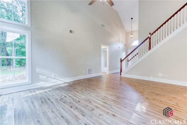 4085 Fawn Vly, Loganville, GA 30052 - unfurnished living room with high vaulted ceiling, wood finished floors, stairs, a ceiling fan, and baseboards