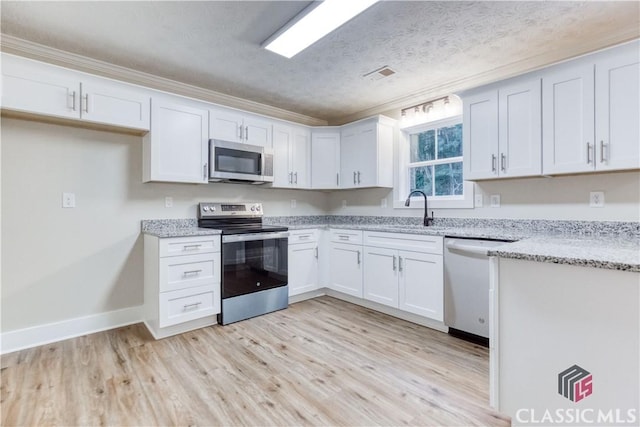 4085 Fawn Vly, Loganville, GA 30052 - kitchen with stainless steel appliances, a sink, light stone counters, white cabinetry, and a textured ceiling