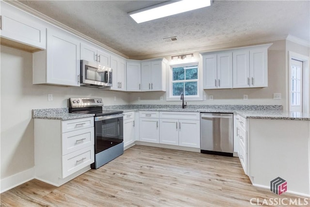 4085 Fawn Vly, Loganville, GA 30052 - kitchen featuring appliances with stainless steel finishes, a sink, crown molding, a textured ceiling, and light wood-style floors