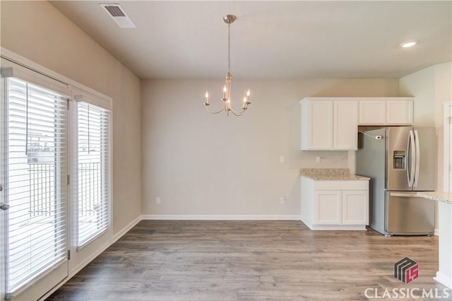 334 Pepin Ct, Hoschton, GA 30548 - kitchen featuring stainless steel refrigerator with ice dispenser, a chandelier, white cabinetry, light stone countertops, and light wood-type flooring