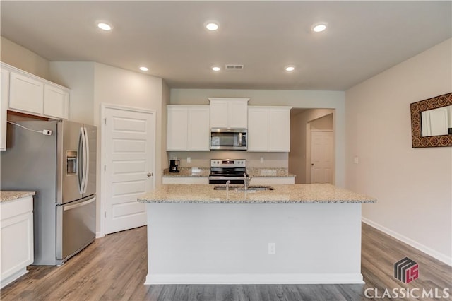 334 Pepin Ct, Hoschton, GA 30548 - kitchen with appliances with stainless steel finishes, a sink, wood finished floors, a center island with sink, and white cabinetry