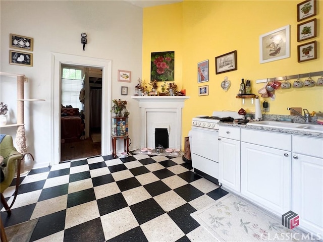 485 Meigs St, Athens, GA 30601 - kitchen with a sink, dark flooring, white gas stove, white cabinets, and a fireplace