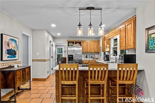 1061 Calls Creek Dr, Watkinsville, GA 30677 - kitchen featuring stainless steel appliances, a sink, a peninsula, a textured wall, and brown cabinets