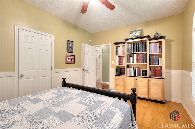 224 Red Oak Dr, Maysville, GA 30558 - bedroom with wainscoting, light wood-style flooring, a textured ceiling, and ceiling fan
