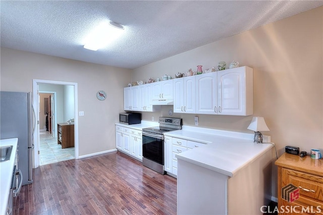 224 Red Oak Dr, Maysville, GA 30558 - kitchen with appliances with stainless steel finishes, white cabinets, dark wood-style flooring, light countertops, and a peninsula