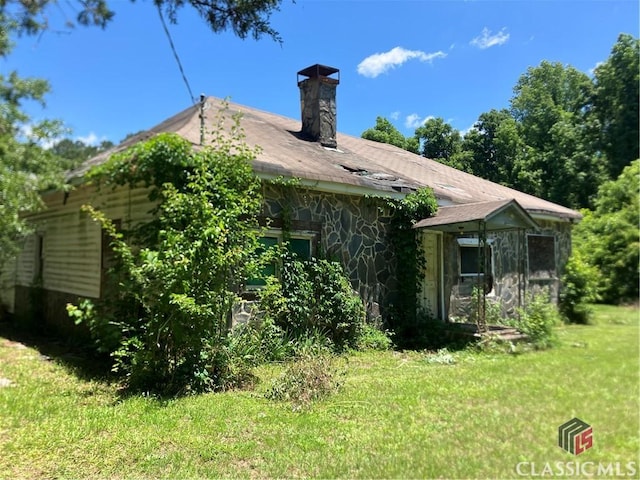 72 N Pomona Rd, Hampton, GA 30228 - rear view of house with stone siding, a chimney, and a lawn