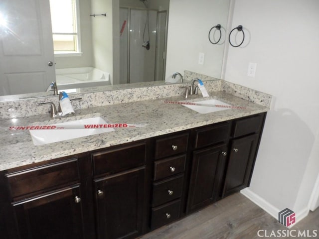 628 Holliman Cir, Pendergrass, GA 30567 - bathroom featuring a stall shower, a garden tub, double vanity, wood finished floors, and baseboards