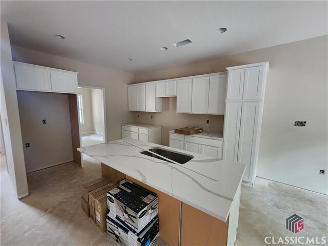 375 Discovery Trl, Athens, GA 30605 - kitchen with unfinished concrete flooring, white cabinetry, an island with sink, light stone countertops, and recessed lighting