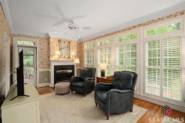 416 Mcdaniel St, Monroe, GA 30655 - living area with crown molding, wallpapered walls, a wainscoted wall, a ceiling fan, and light wood-type flooring