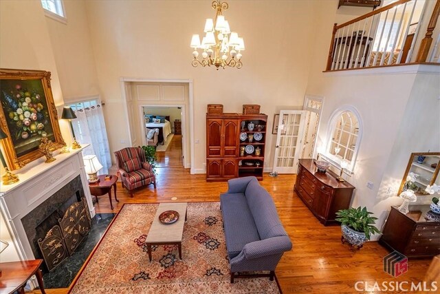 416 Mcdaniel St, Monroe, GA 30655 - living area with a high ceiling, wood finished floors, a chandelier, a high end fireplace, and baseboards