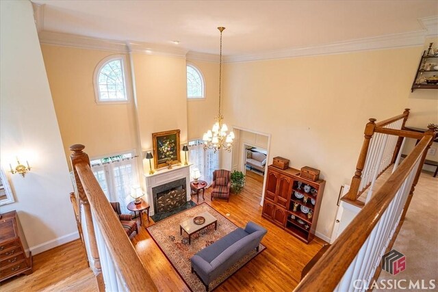 416 Mcdaniel St, Monroe, GA 30655 - living area featuring wood finished floors, a fireplace with flush hearth, a chandelier, crown molding, and baseboards
