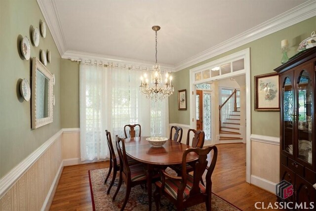 416 Mcdaniel St, Monroe, GA 30655 - dining area with a chandelier, crown molding, wainscoting, wood finished floors, and stairway