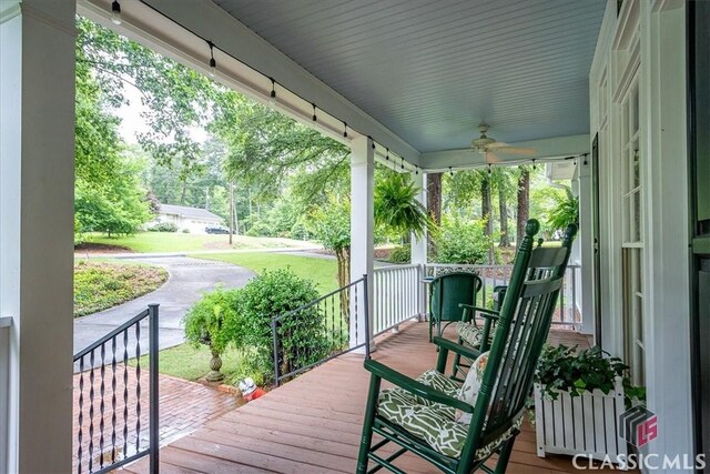 416 Mcdaniel St, Monroe, GA 30655 - wooden porch featuring ceiling fan, view of wooded area, and a lawn