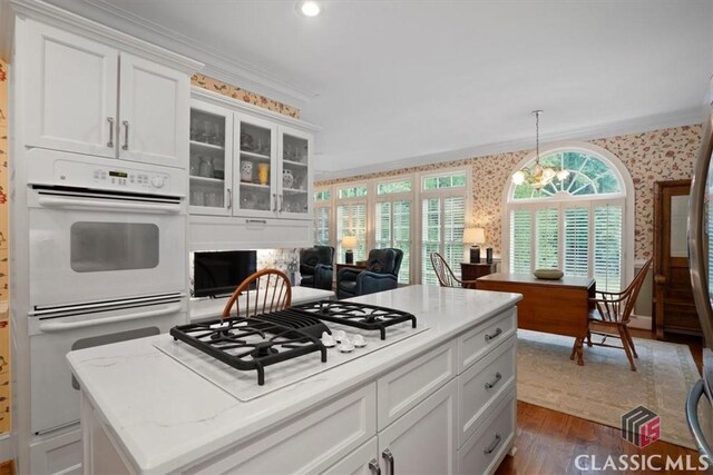 416 Mcdaniel St, Monroe, GA 30655 - kitchen with wallpapered walls, white appliances, crown molding, dark wood finished floors, and white cabinets