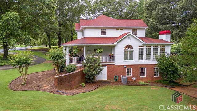 416 Mcdaniel St, Monroe, GA 30655 - view of front of house featuring a front lawn, a chimney, central AC unit, view of wooded area, and brick siding