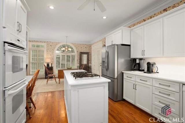 416 Mcdaniel St, Monroe, GA 30655 - kitchen with wallpapered walls, white appliances, a center island, white cabinets, and light countertops