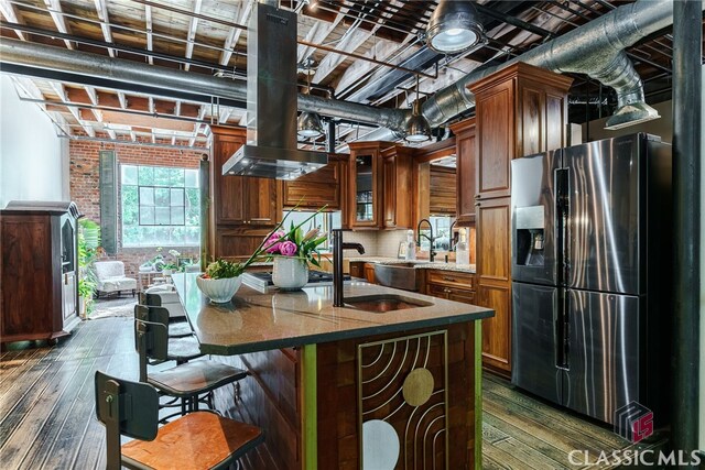 585 White Cir Unit 406, Athens, GA 30605 - kitchen featuring stainless steel refrigerator with ice dispenser, dark wood-type flooring, brown cabinets, brick wall, and an island with sink
