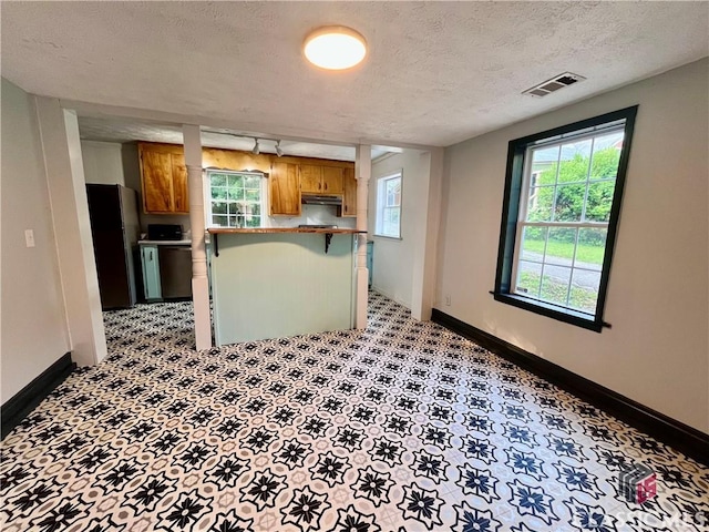 180 N Poplar St, Athens, GA 30601 - kitchen featuring freestanding refrigerator, under cabinet range hood, baseboards, brown cabinets, and a textured ceiling