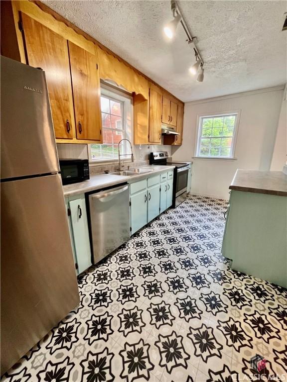 180 N Poplar St, Athens, GA 30601 - kitchen with appliances with stainless steel finishes, a sink, under cabinet range hood, light countertops, and a textured ceiling