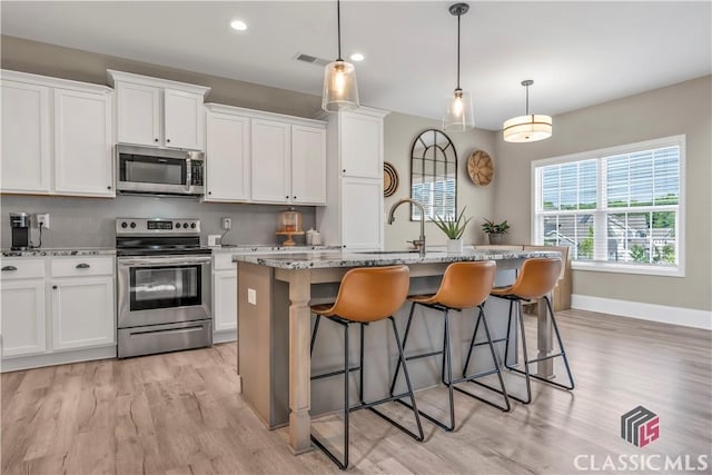 1810 Willow Creek Dr, Watkinsville, GA 30677 - kitchen featuring appliances with stainless steel finishes, light wood-style flooring, a kitchen breakfast bar, white cabinetry, and recessed lighting