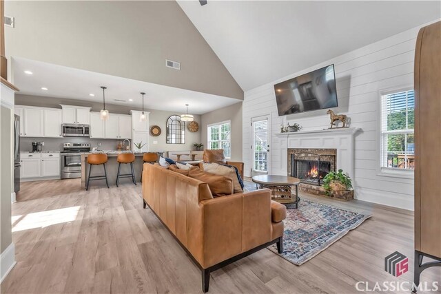 1810 Willow Creek Dr, Watkinsville, GA 30677 - living room featuring light wood-type flooring, healthy amount of natural light, high vaulted ceiling, a warm lit fireplace, and recessed lighting