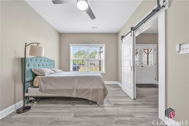 1810 Willow Creek Dr, Watkinsville, GA 30677 - bedroom with a barn door, wood finished floors, and baseboards