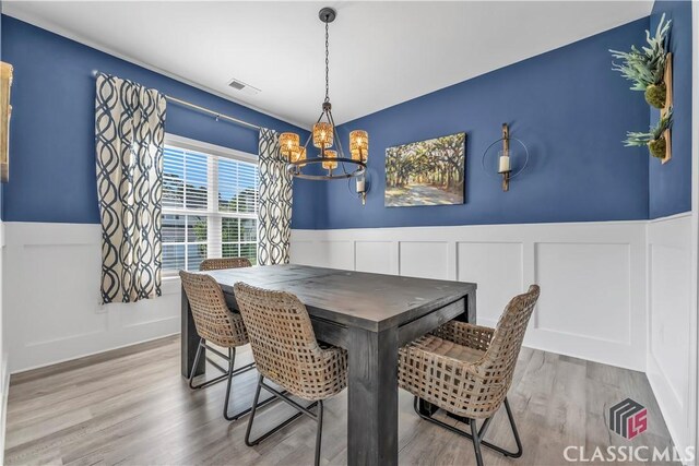 1810 Willow Creek Dr, Watkinsville, GA 30677 - dining space featuring a chandelier, a decorative wall, wainscoting, and wood finished floors