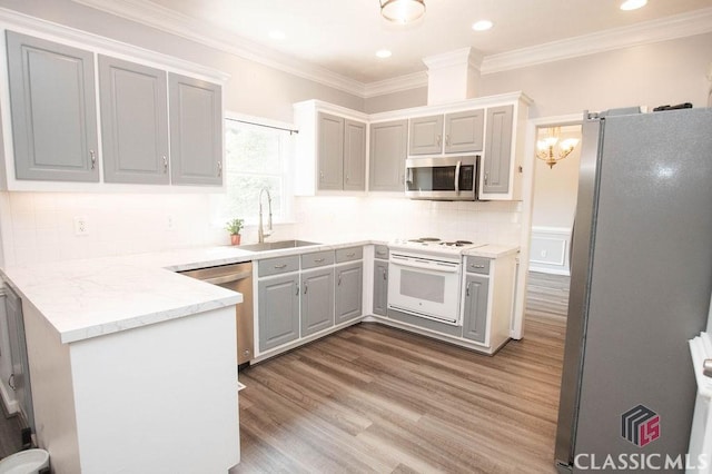1851 Harvest Way, Loganville, GA 30052 - kitchen with stainless steel appliances, a sink, light wood finished floors, a peninsula, and ornamental molding