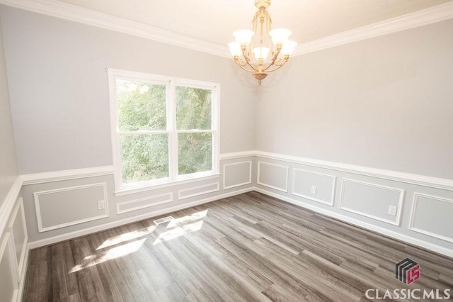 1851 Harvest Way, Loganville, GA 30052 - unfurnished room with a chandelier, a decorative wall, wood finished floors, crown molding, and a wainscoted wall