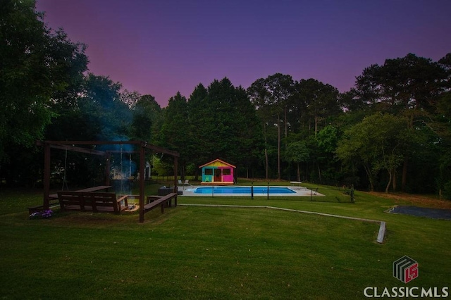 1851 Harvest Way, Loganville, GA 30052 - pool at dusk featuring a lawn, an outdoor pool, an outdoor structure, and a diving board