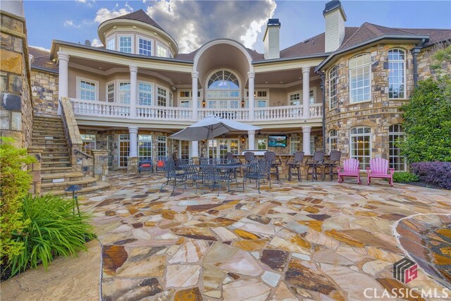 3881 Sims Bridge Rd, Monroe, GA 30656 - rear view of house featuring stone siding, stairs, a patio, a balcony, and a chimney