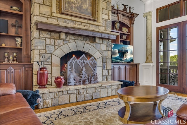 3881 Sims Bridge Rd, Monroe, GA 30656 - living room featuring built in shelves, wood finished floors, a stone fireplace, ornamental molding, and decorative columns