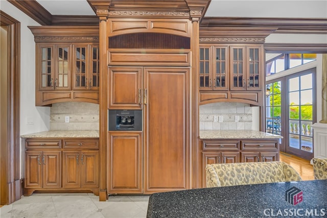 3881 Sims Bridge Rd, Monroe, GA 30656 - kitchen featuring backsplash, light stone counters, crown molding, glass insert cabinets, and brown cabinetry
