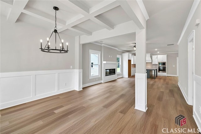 231 Marable St E, Monroe, GA 30655 - unfurnished living room featuring coffered ceiling, ceiling fan, a glass covered fireplace, a chandelier, and beam ceiling