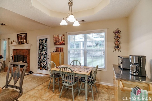 1663 Oconee Pt, Jefferson, GA 30549 - dining space featuring plenty of natural light, a tray ceiling, a fireplace, and a chandelier